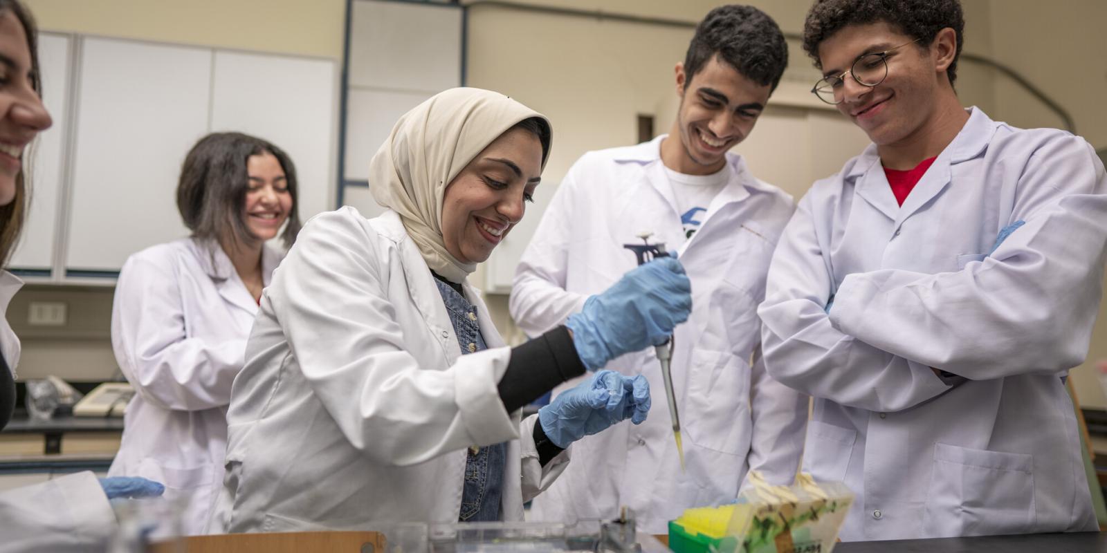 group of students wearing white coats in lab working on a project