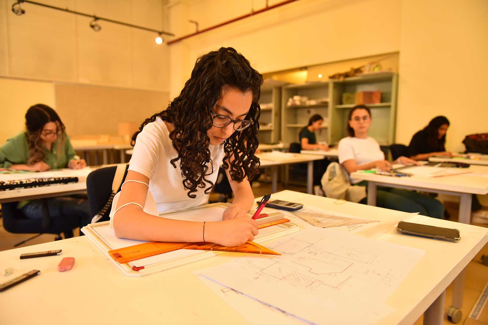 female student drawing on the drawing board with architectural equipment