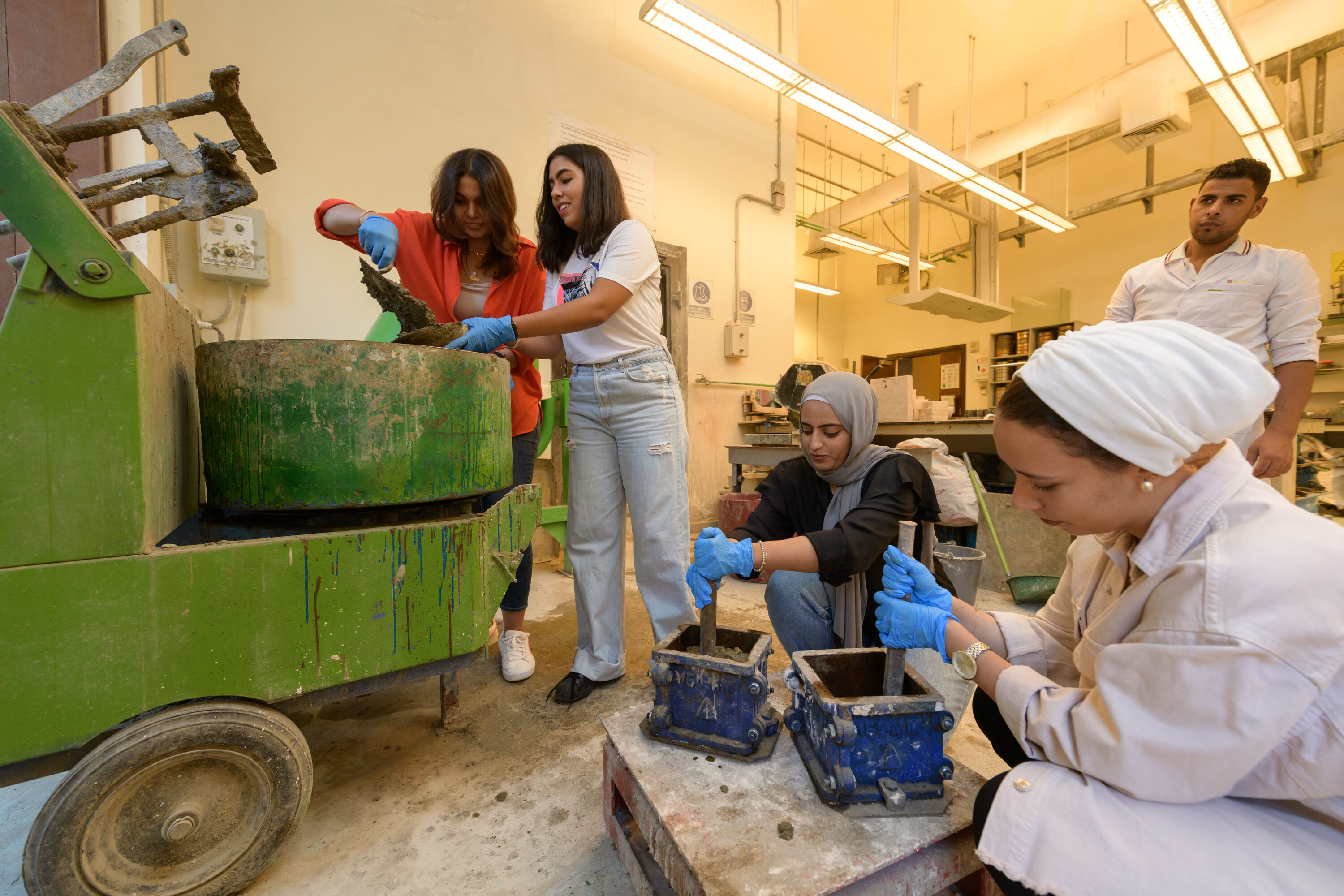 female students working with cement and construction engineering equipment in lab