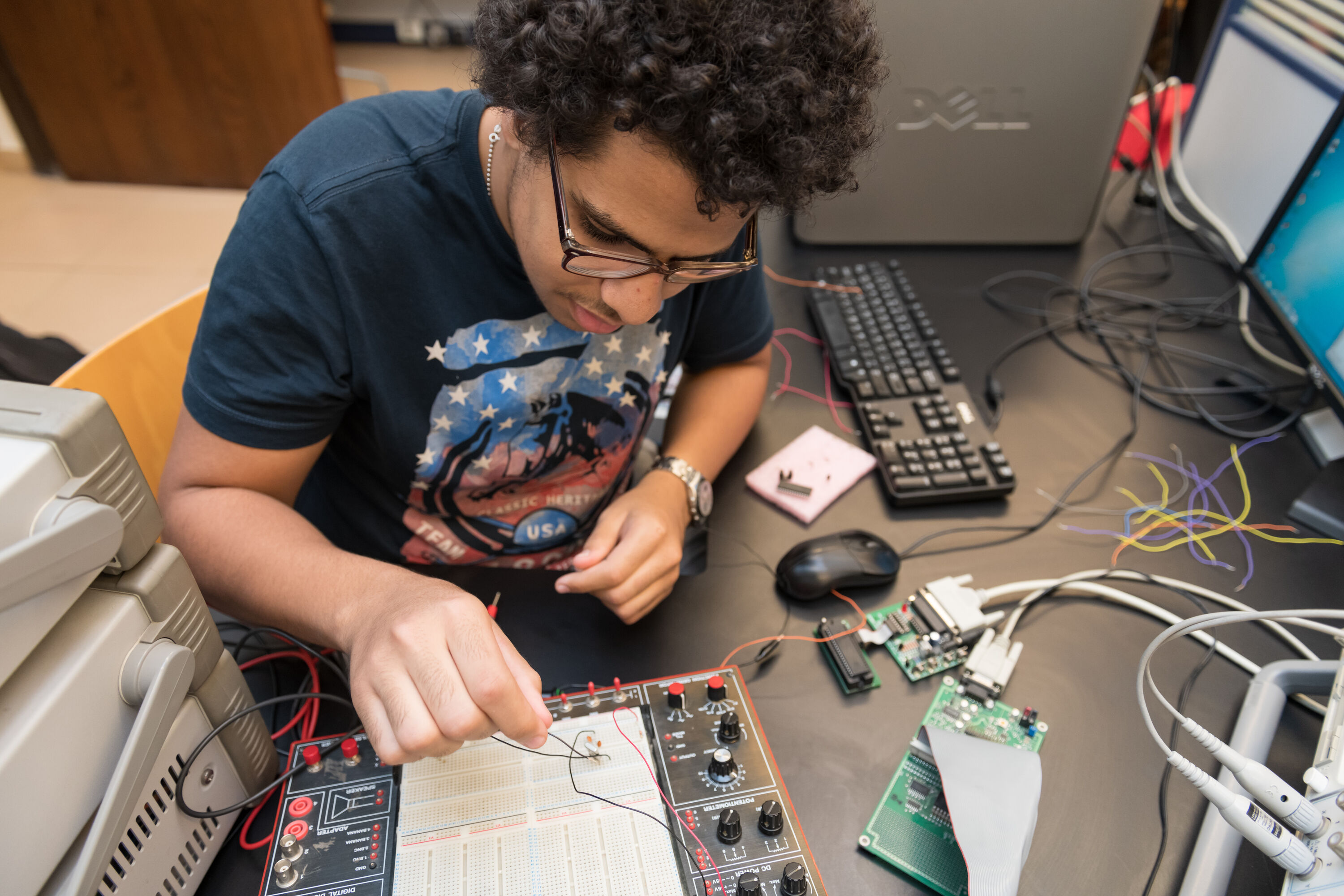 electronics and communications program image of male student working with electronic equipment in science lab
