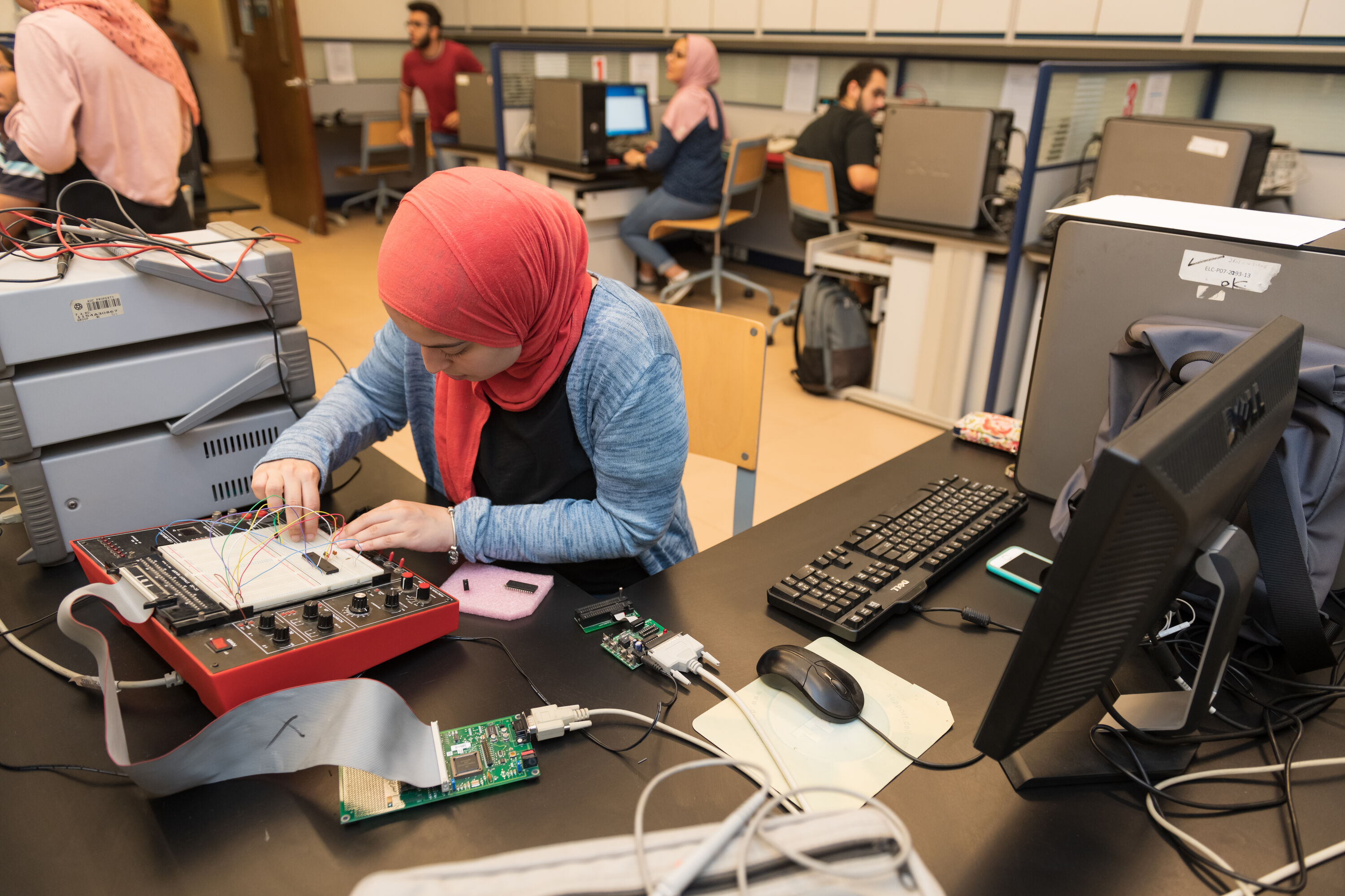 electronics and communications program image of female student working with electronic program inside science lab