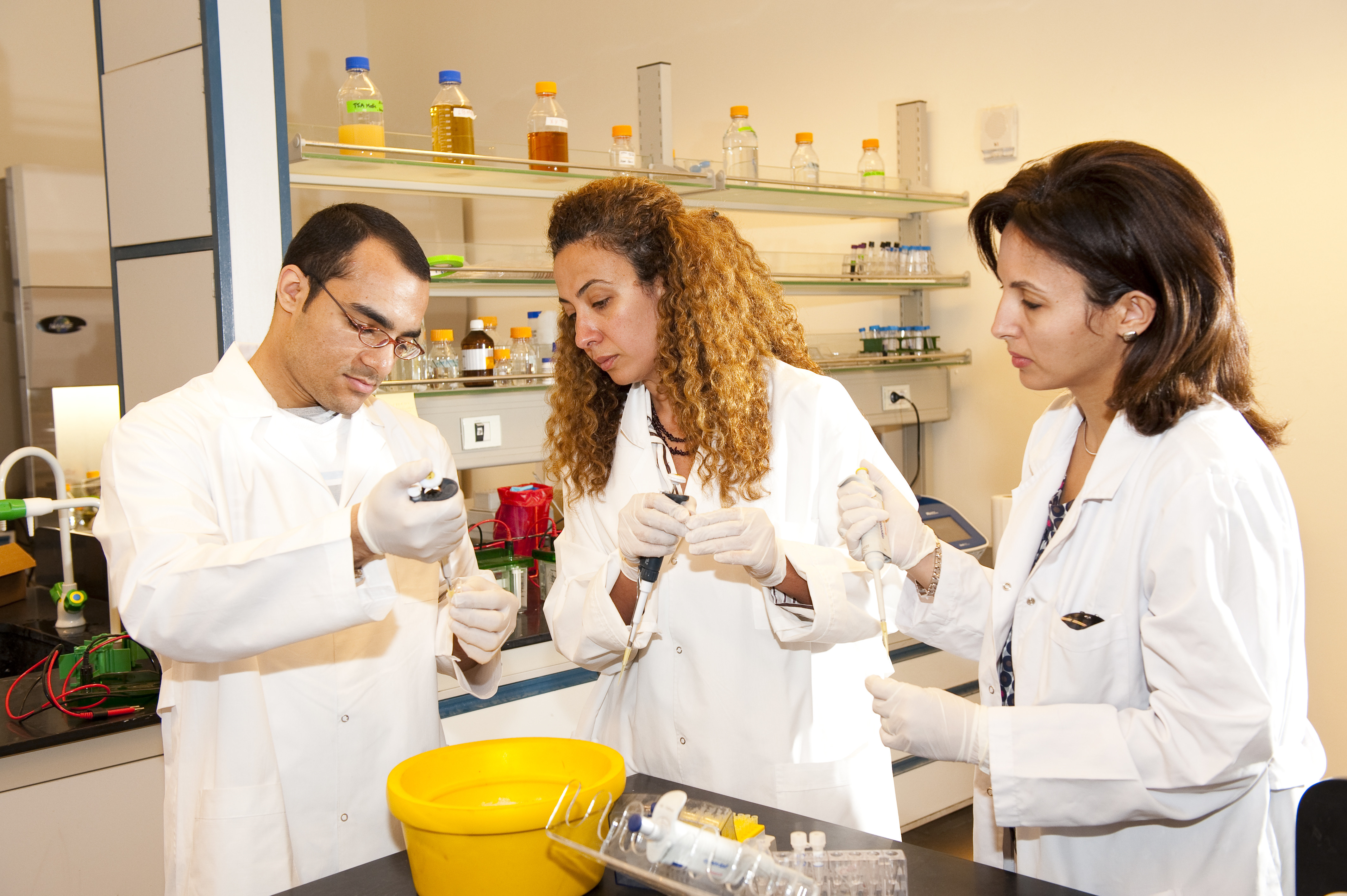 Professor and students in lab with white coats holding test tubes