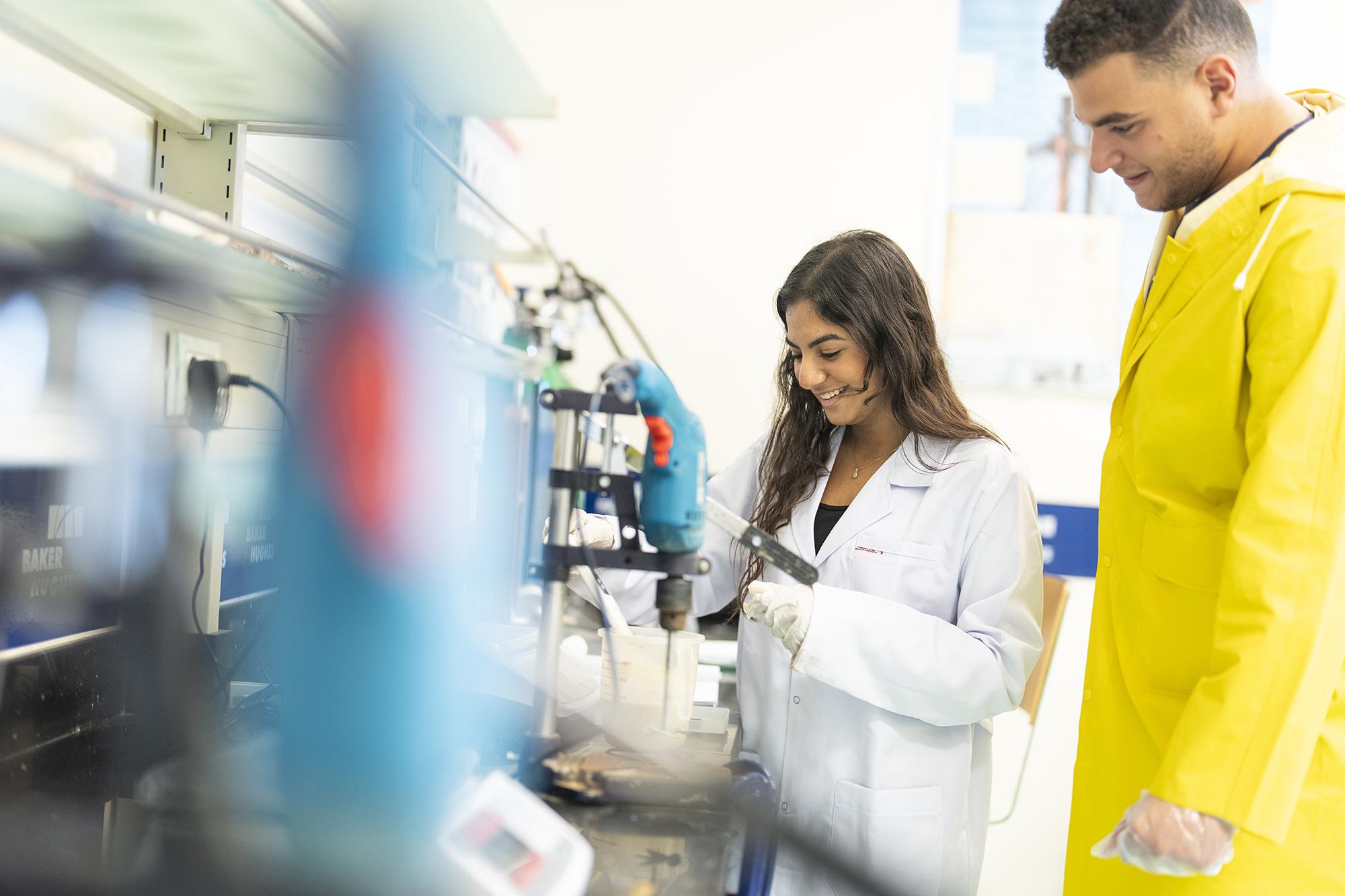 students working with medical equipment wearing white coats in lab