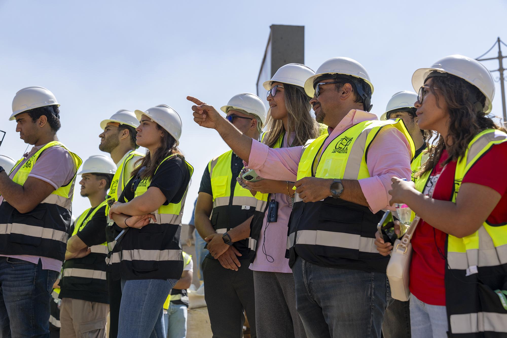 students with faculty on construction site wearing safety gear
