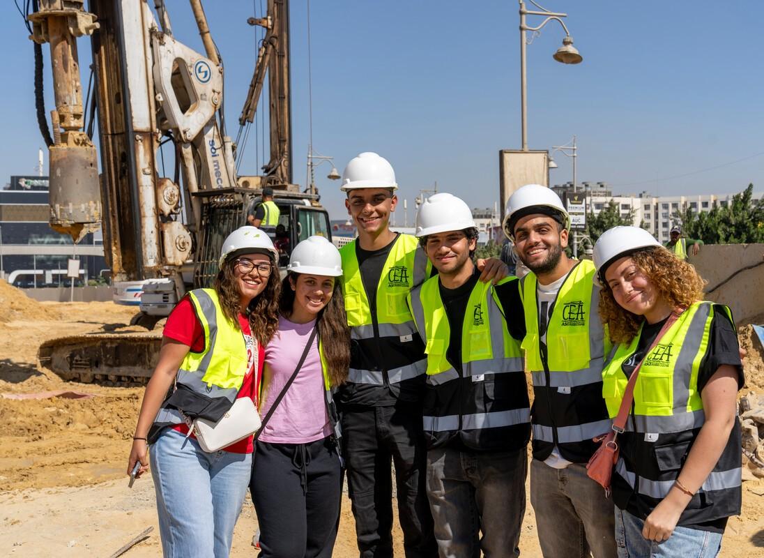 smiling construction students wearing yellow vests on construction site