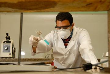 Man standing in a chemistry lab holding a test tube