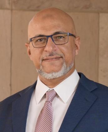 Headshot of man smiling wearing a suit and tie