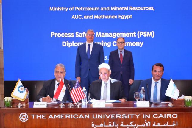 Senior officials from AUC, including the president and provost, sit and stand at a table to sign a memorandum of understanding.