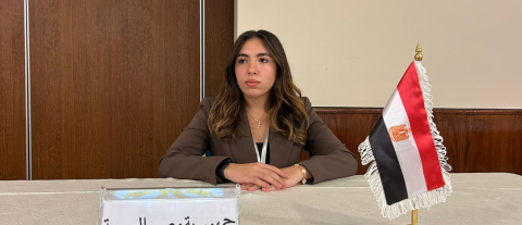 Maysem Alagamy sitting behind a mini Egyptian flag and placard