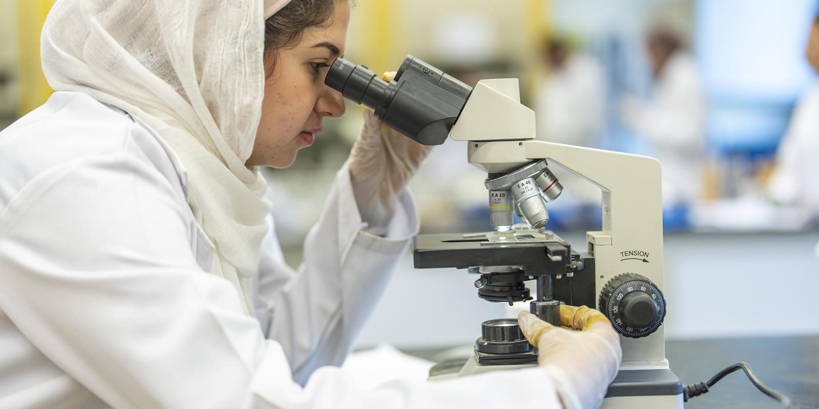 female student using a microscope