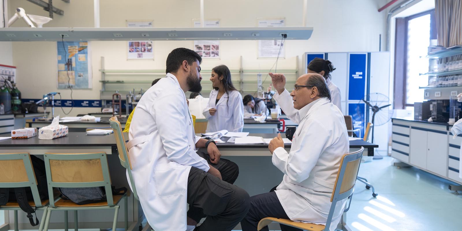 students working in lab wearing white coats