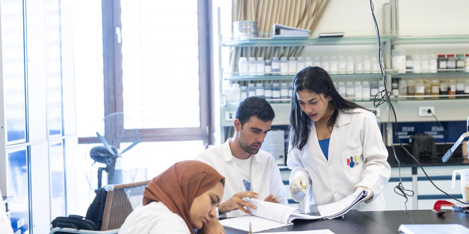 students in white lab coats conducting experiments
