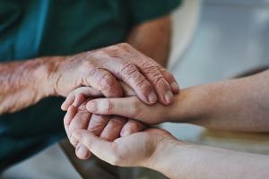 A pair of old hands comfort a pair of young hands.