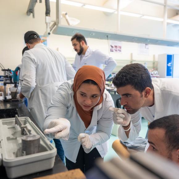 students wearing white lab coats working together on an experiment